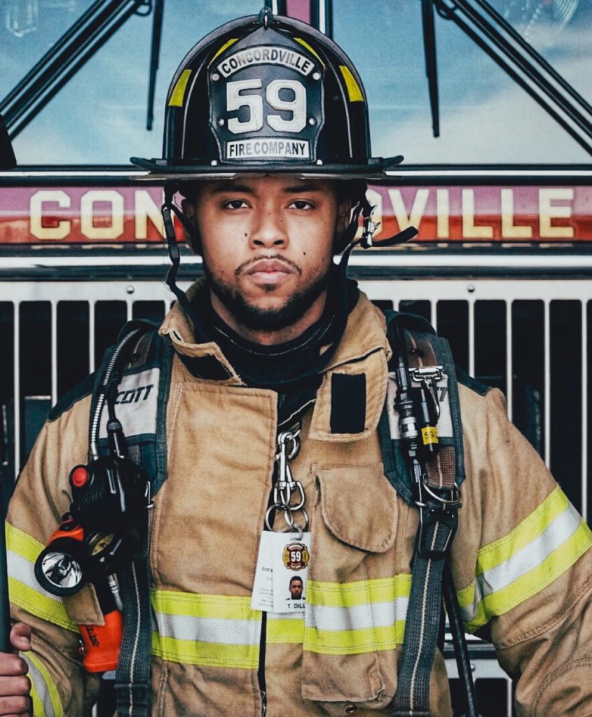 A photograph of a firefighter from the 59th Concordville Fire Company looking straight into the camera, standing in front of a firetruck.